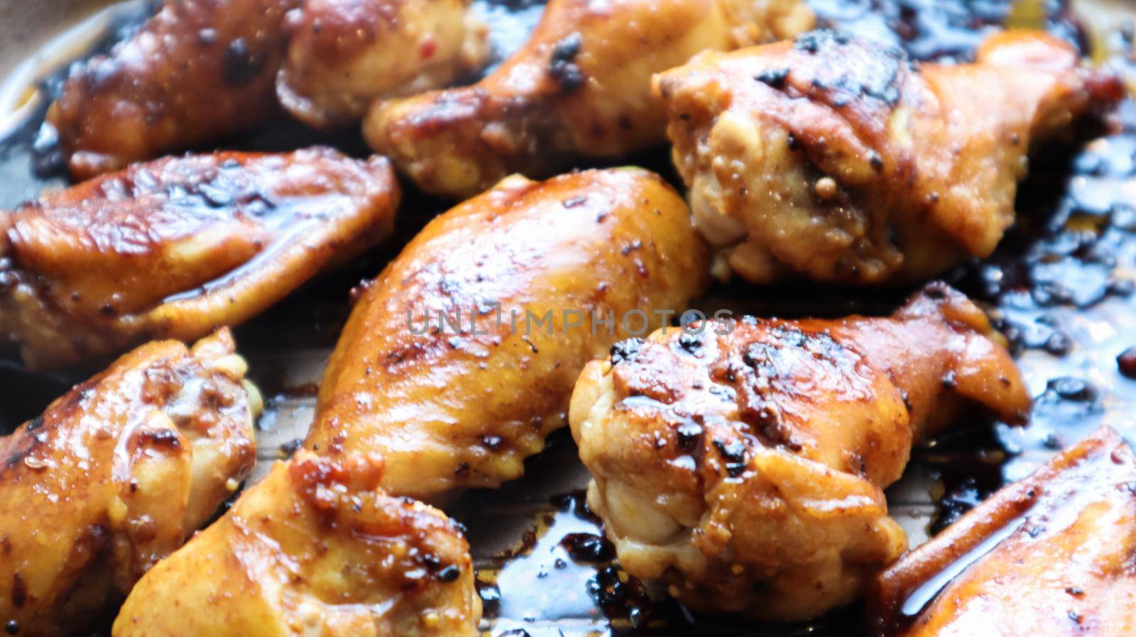 Fried chicken wings with a crust in a pan close-up. Baked chicken in teriyaki sauce on a baking sheet in the oven, selective focus