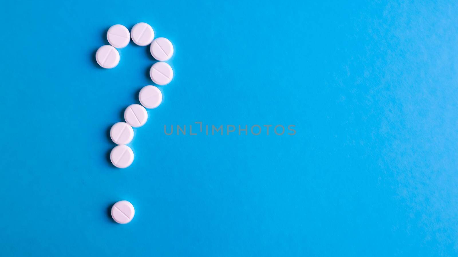 Question mark made of many white pills on a blue background. Healthcare concept. Creative medicine for health medical problem, drug interaction, medication error and pharmaceutical concept