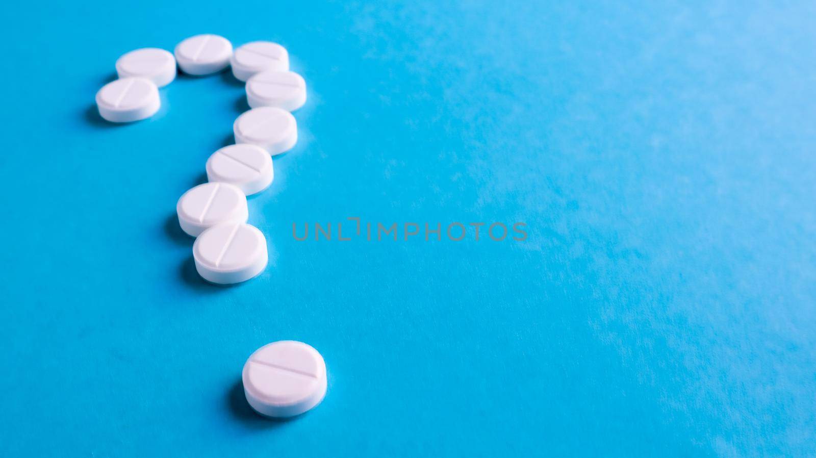 Question mark made of many white pills on a blue background. Healthcare concept. Creative medicine for health medical problem, drug interaction, medication error and pharmaceutical concept