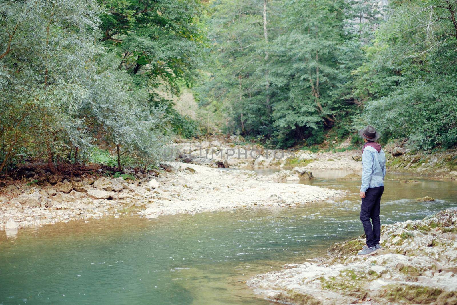 Explorer young man standing on the river bank and enjoying view of nature.