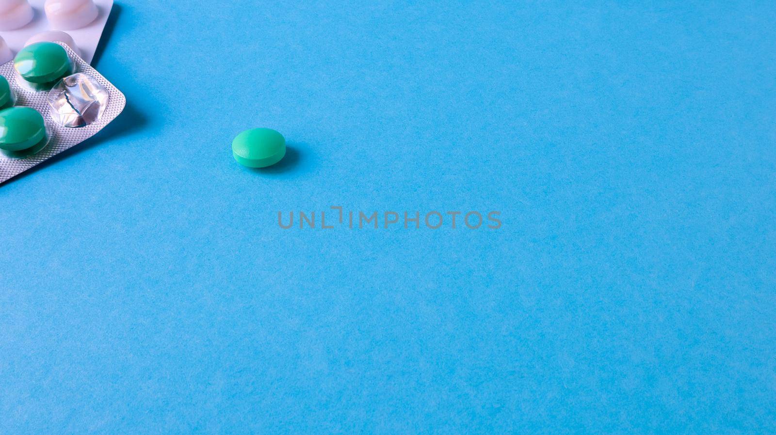 Two packs of pills and one round pill to the side on a blue background with copy space. antiviral tablets for pneumonia and bacterial infection. medicines and wellness treatments