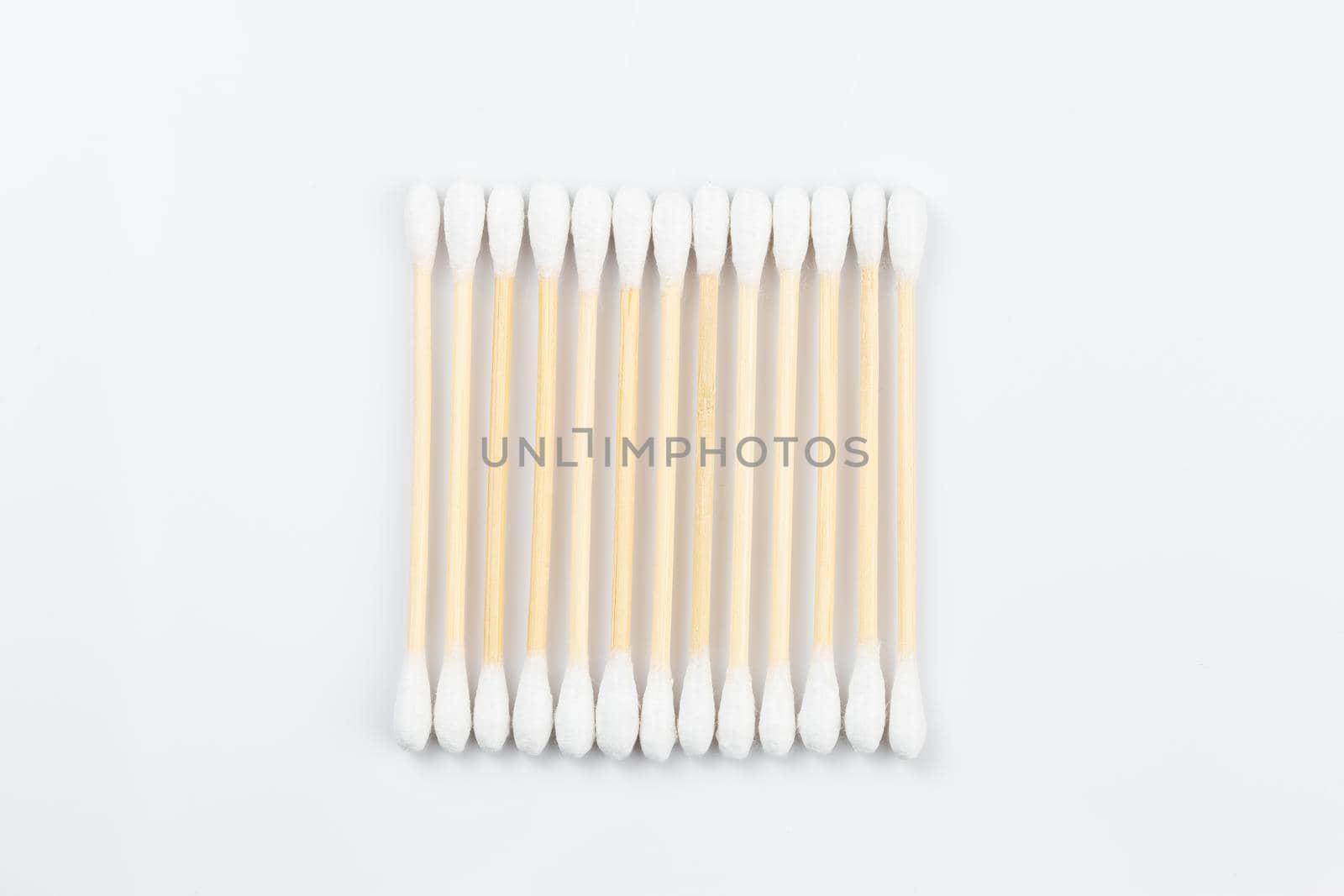 Wooden cotton swabs in a row on white background. Sustainable lifestyle concept