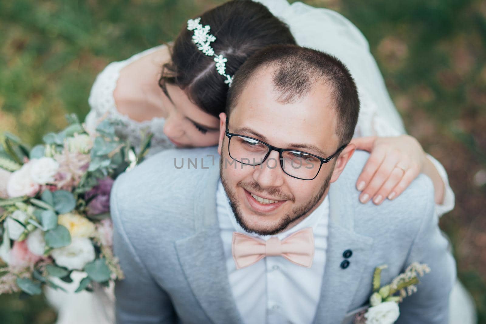 Bride and groom on wedding day, hugging, stand near the cliff and look up.