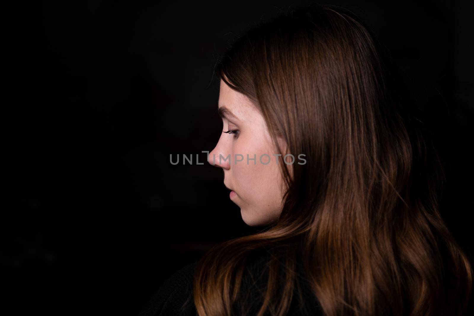 Studio black background dark black clothes portrait girl evening reception profile side brunette hair looks edge frame. Copy space left