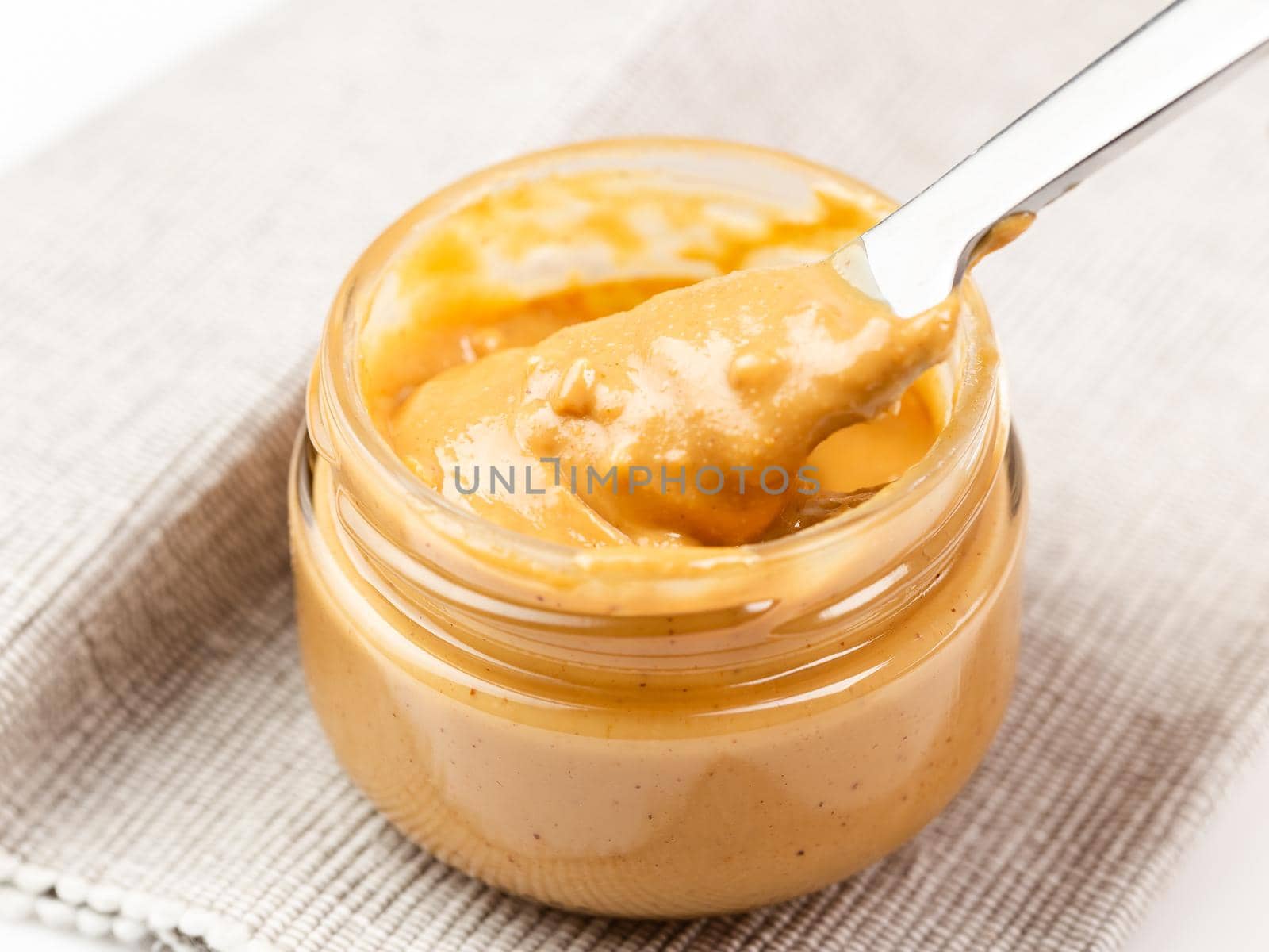 Crunchy peanut butter in a glass jar, close up