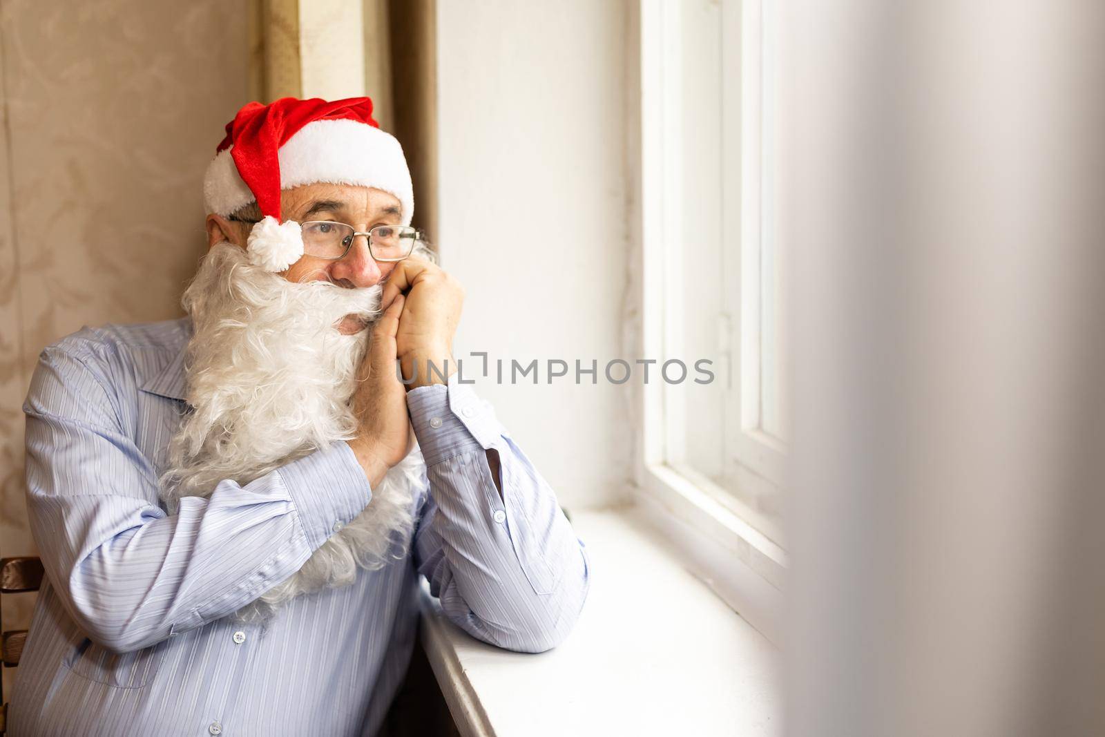 Portrait of happy senior man in Santa hat preparing for Christmas by Andelov13