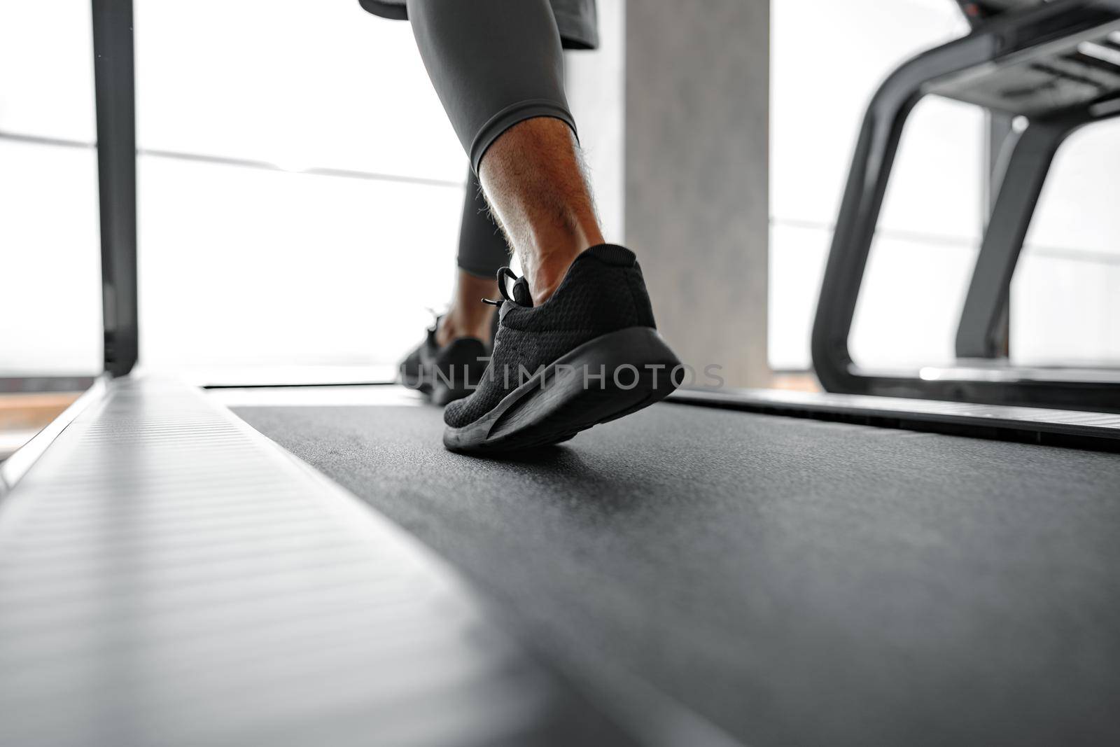 Close up photo of male legs running in a gym on a treadmill