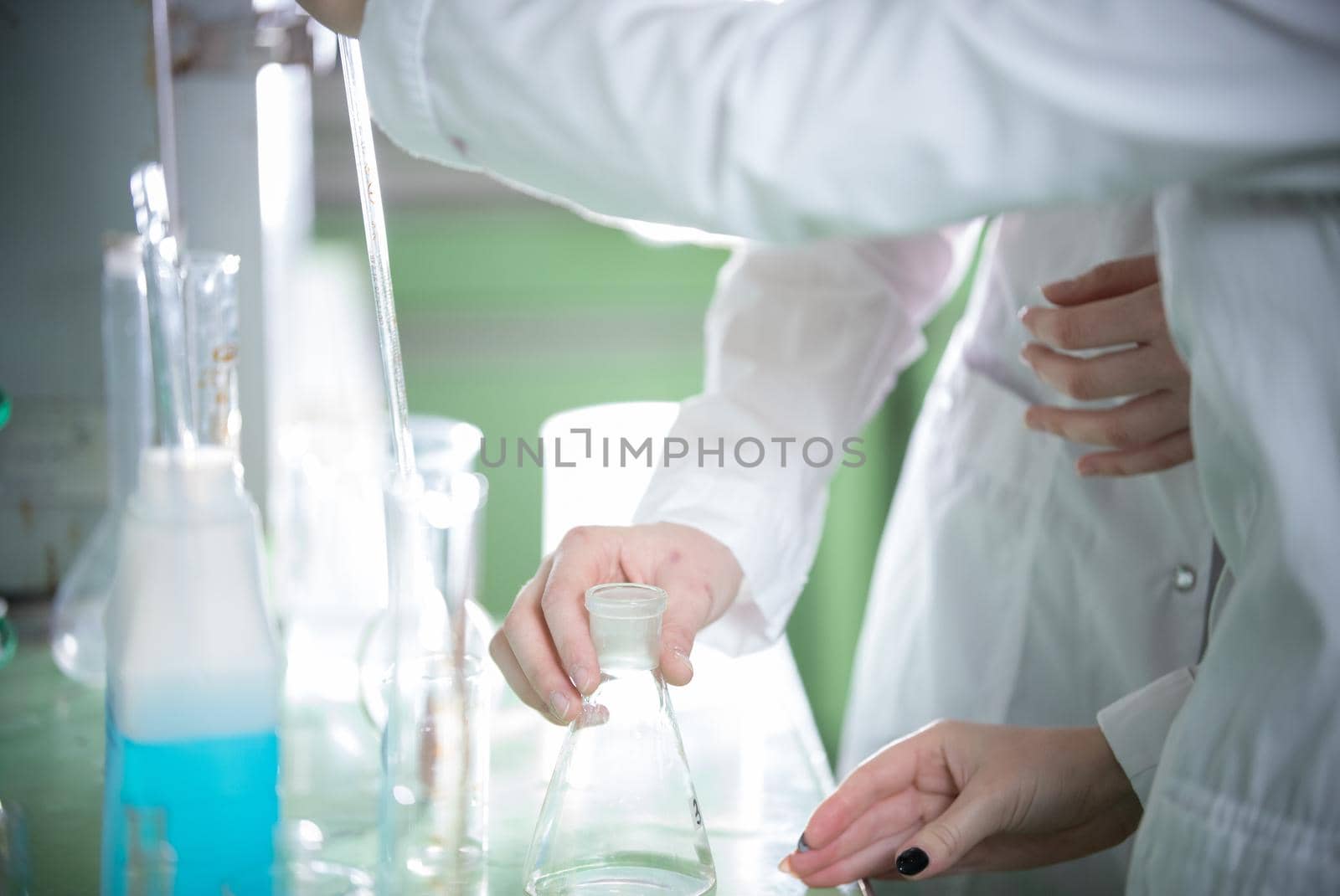 Chemical laboratory. Two young woman holding a flask. Hands in focus