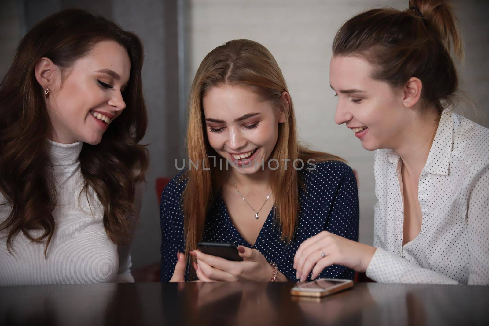 Young beautiful women sitting in a bar looking on telephone. Portrait