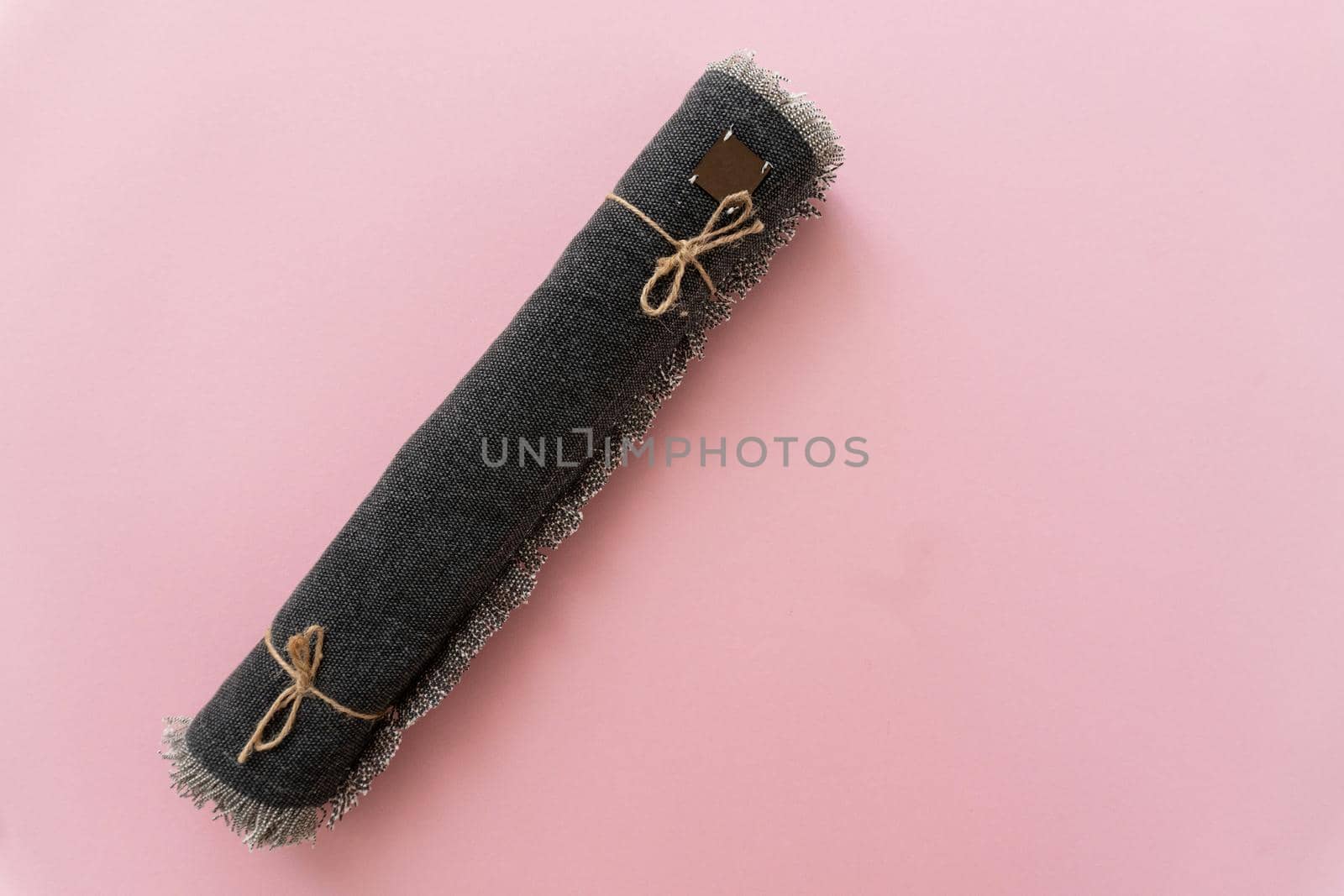 Close up at the rolled table runner, linen table cloth on pink background, kitchen serviettes concept, copy space, texp place.