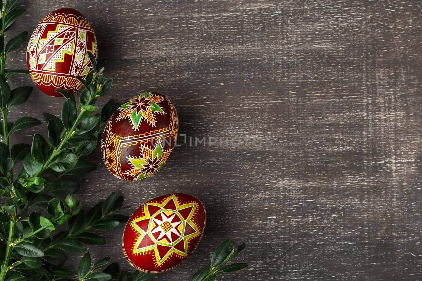 Handmade Easter eggs. Ukrainian pysanka decorated with wax-resist dyeing technique. Grey shabby background with copy empty space for text