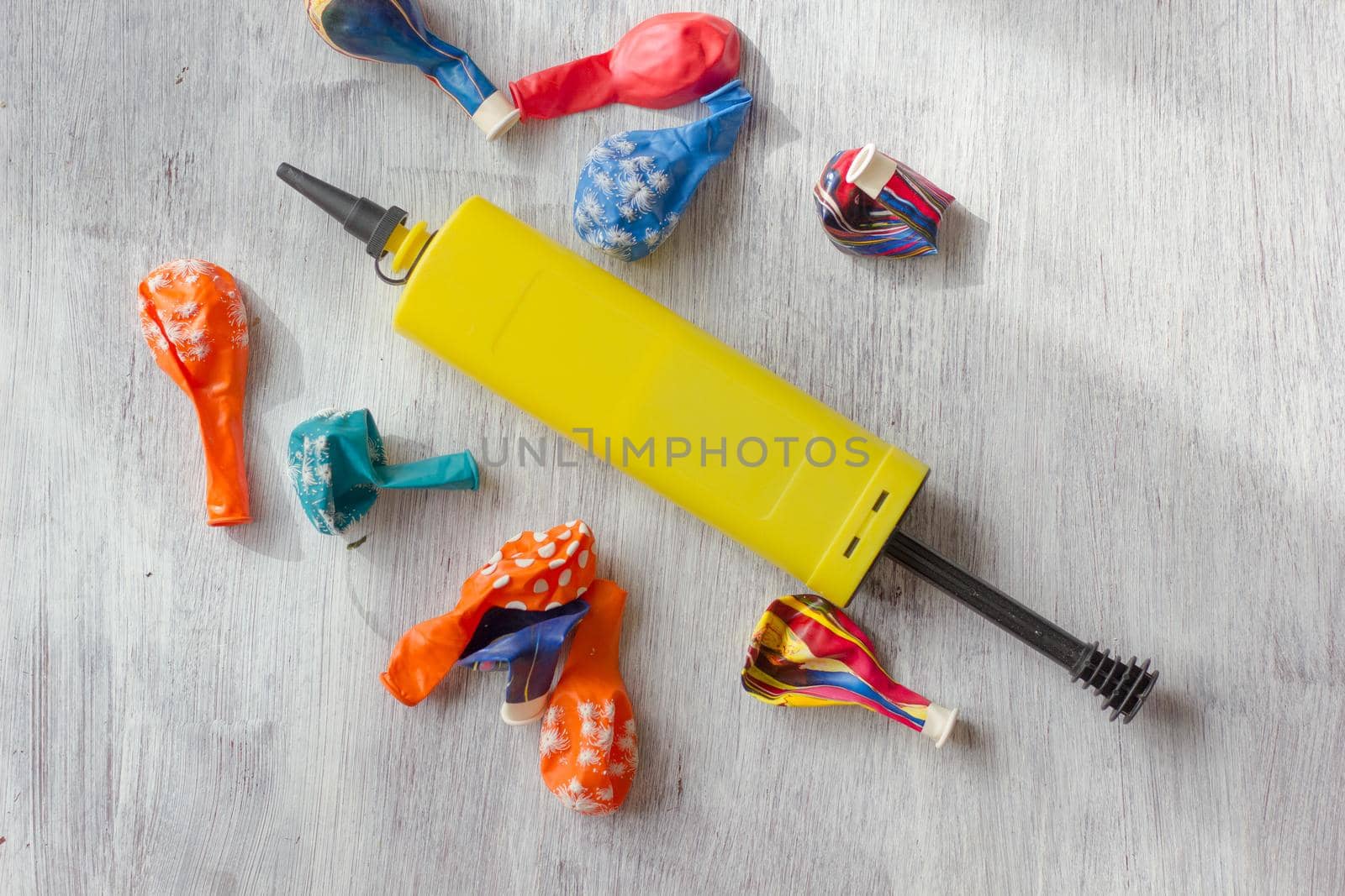 Yellow pump for blowing balloons with vivid balloons on a table