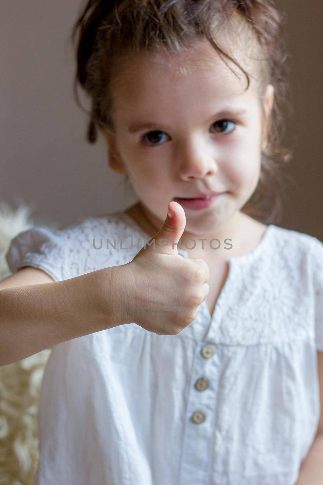 Cute Little kid girl holds thumb up.