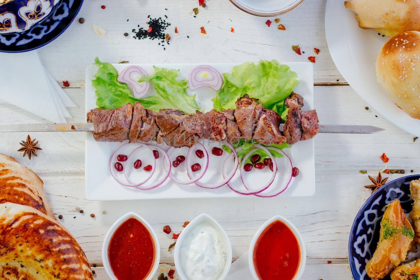 Top view of grilled meat on skewer, over the white plate, with sauces, great image for your needs.