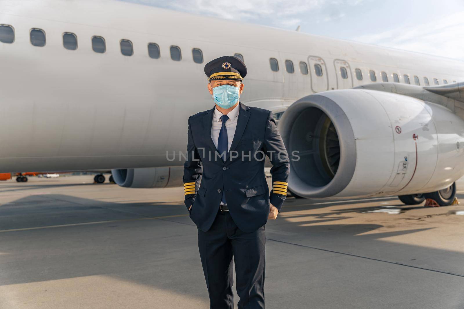 Airline pilot in mask standing near aircraft by Yaroslav_astakhov