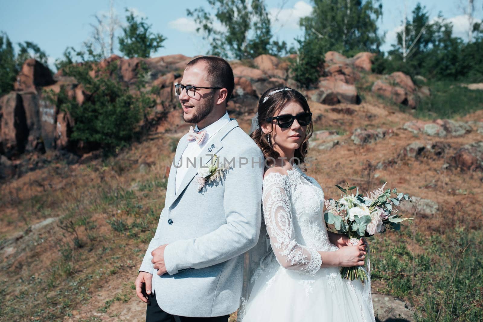Wedding photography fashionable bride and groom in sunglasses on the nature on the rocks