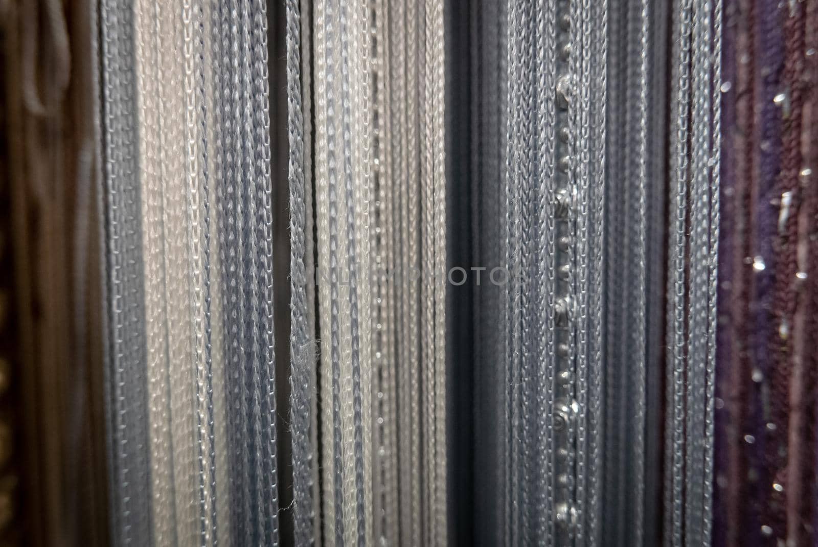 Textile strings and ropes hangs in a fabric shop. Abstract background