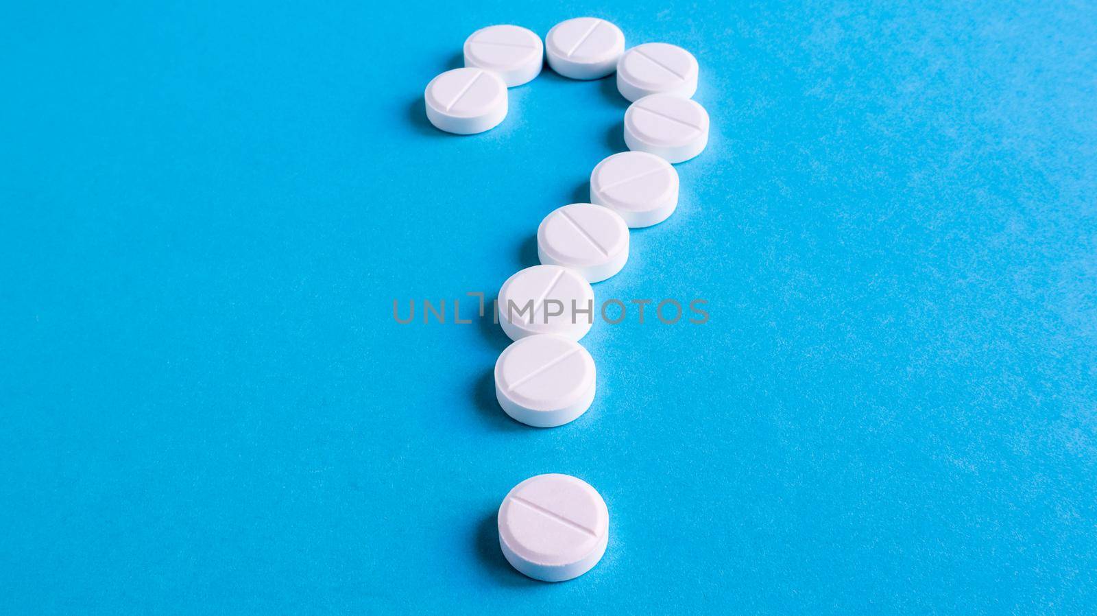 Question mark made of many white pills on a blue background. Healthcare concept. Creative medicine for health medical problem, drug interaction, medication error and pharmaceutical concept