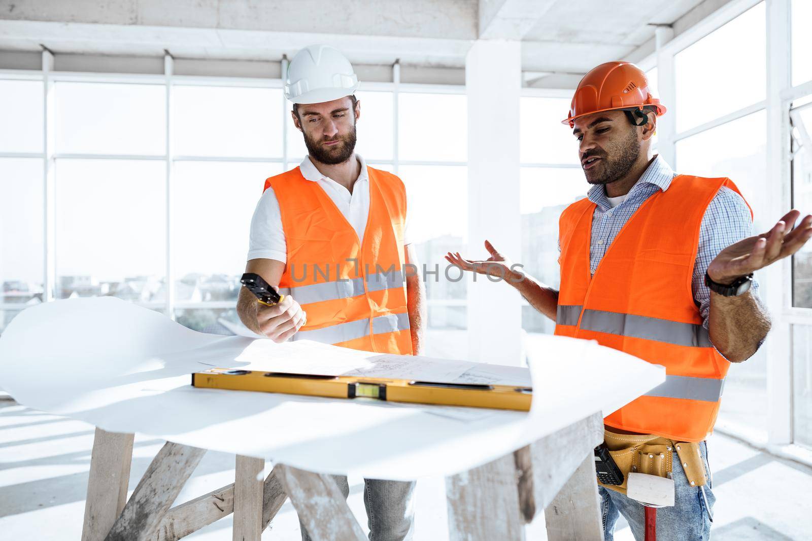 Two young engineers man looking at project plan on the table in construction site