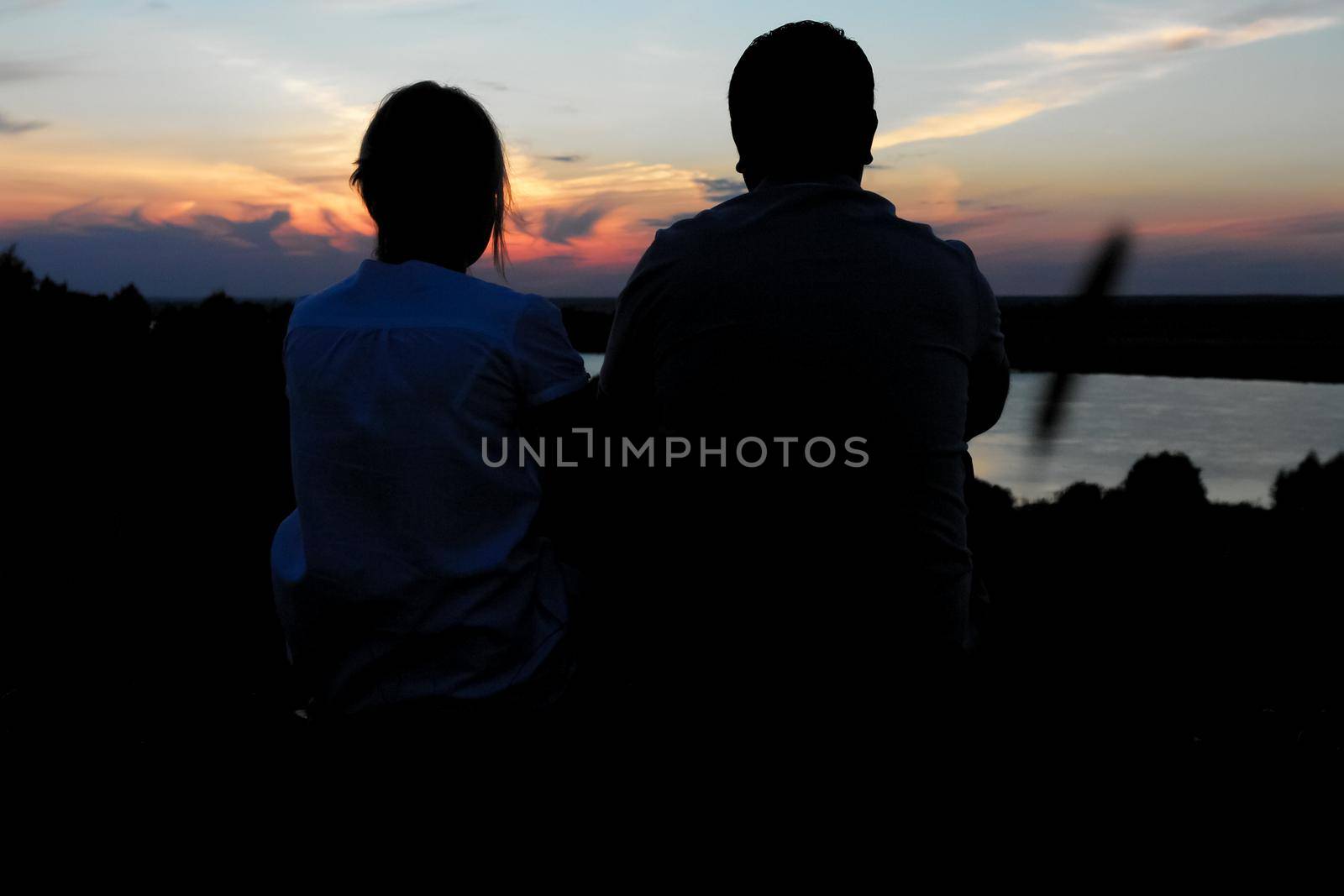 Young couple silhouette against sunset sky. Romantic eveningn.