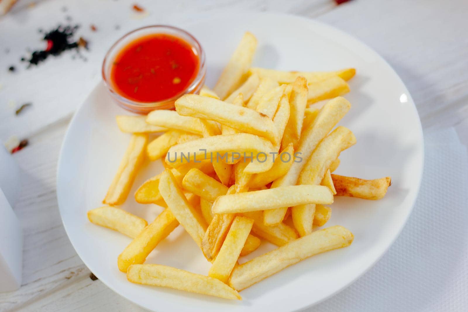 French fries with red tomato sauce on the white plate, great image for your needs.