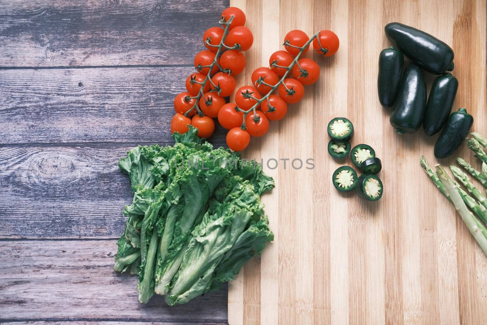 Jalapeno peppers , asparagus, cherry tomato, lettuce on chopping board .