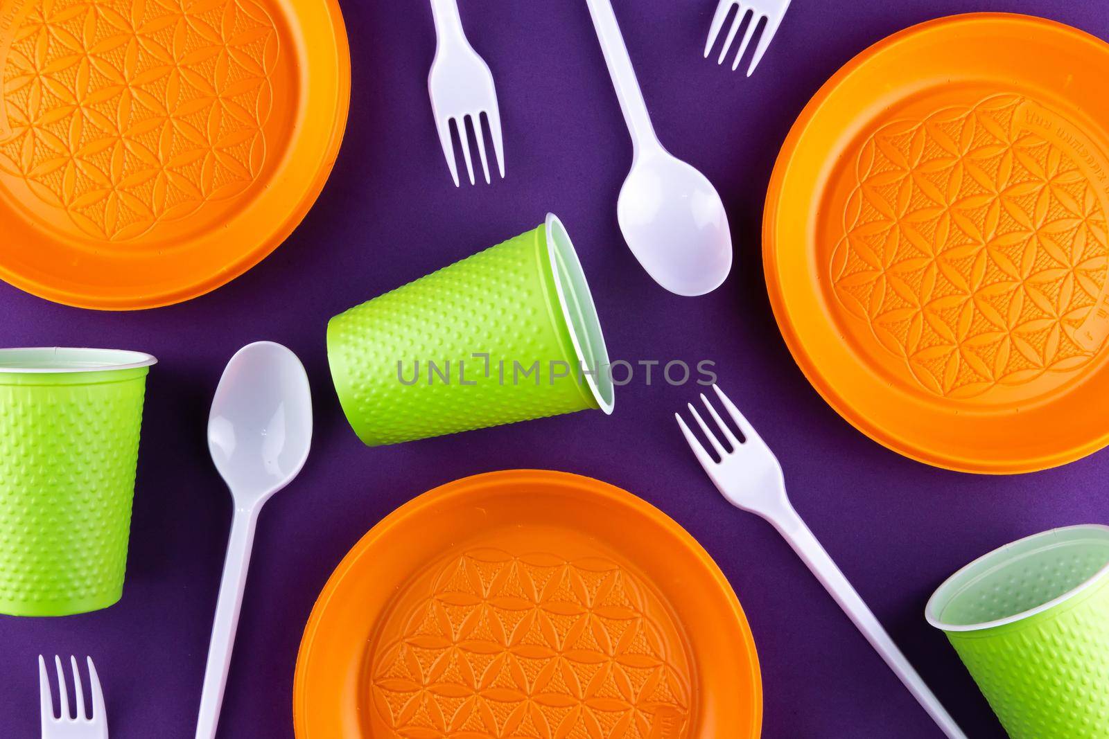 Plastic orange green waste collection on purple background. Concept of plastic pollution and ecology problem