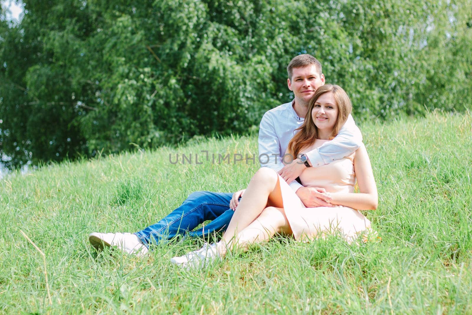 Lovely couple sitting near each other at grass lawn at nature park