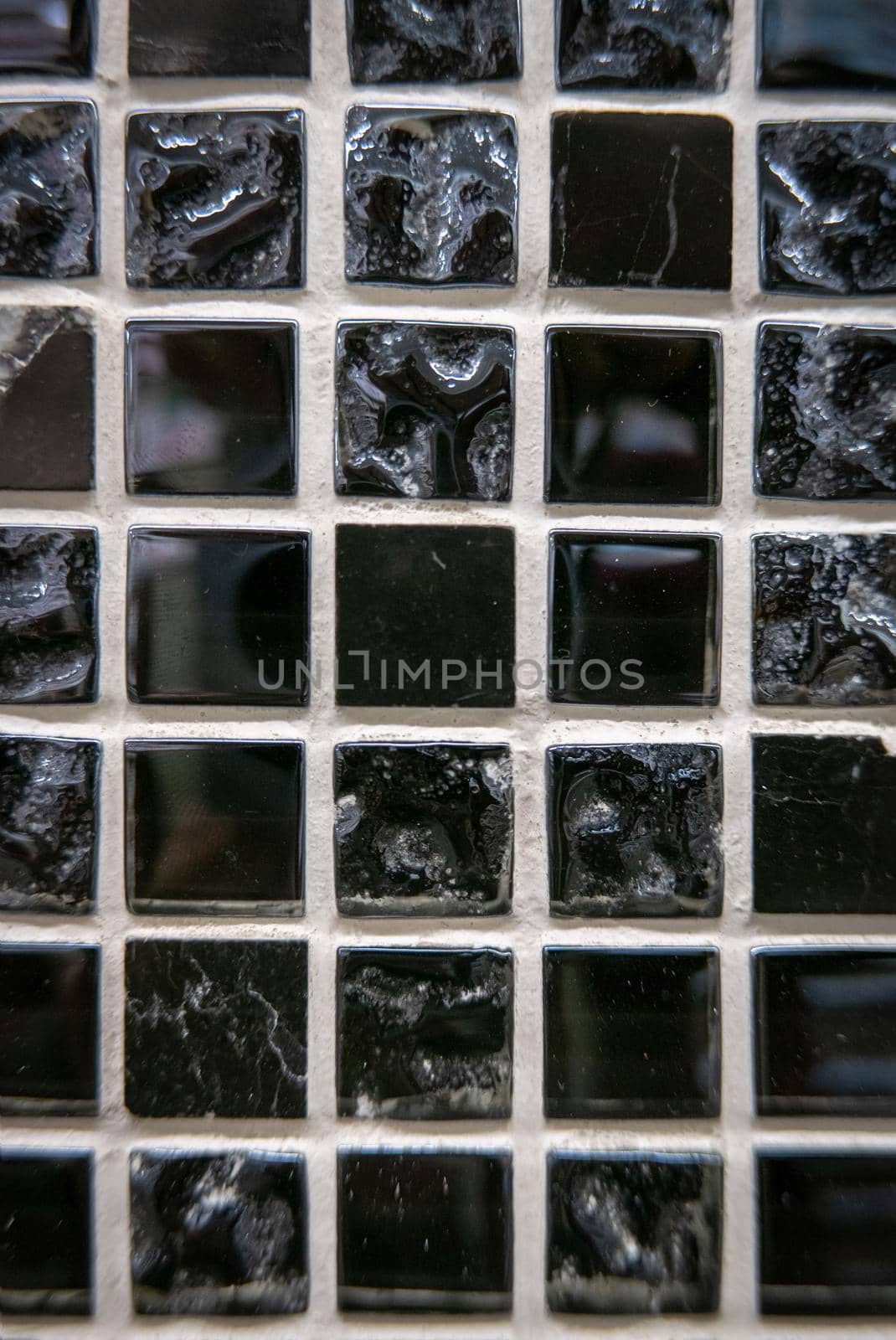 Black ceramic mosaic on the wall as background.