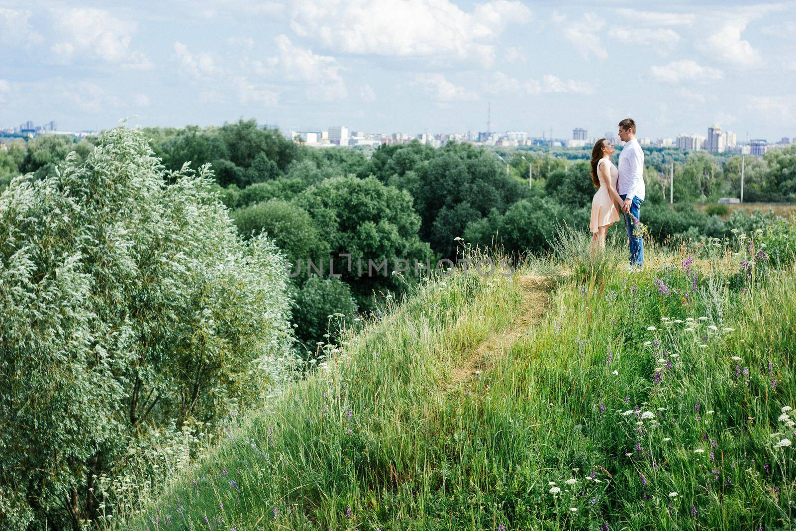 Lovely young couple look to each other against the city, nature and sky