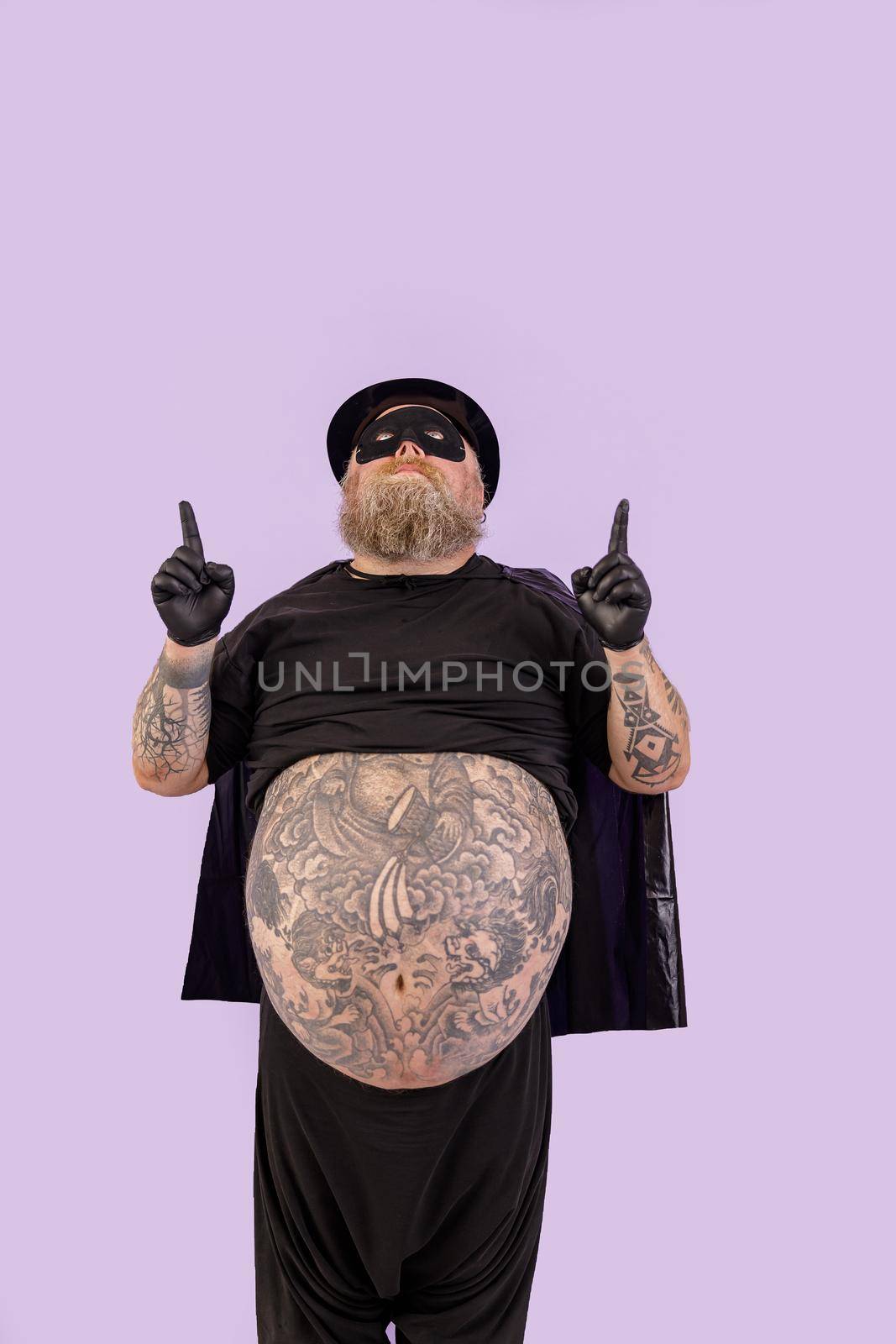 Obese man in black hero suit looks and points up standing on purple background by Yaroslav_astakhov