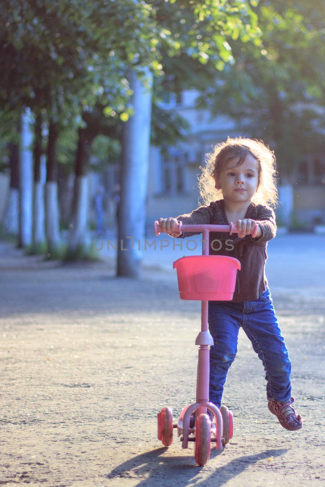 Yong kid girl ride on street with child scooter by sharafizdushanbe