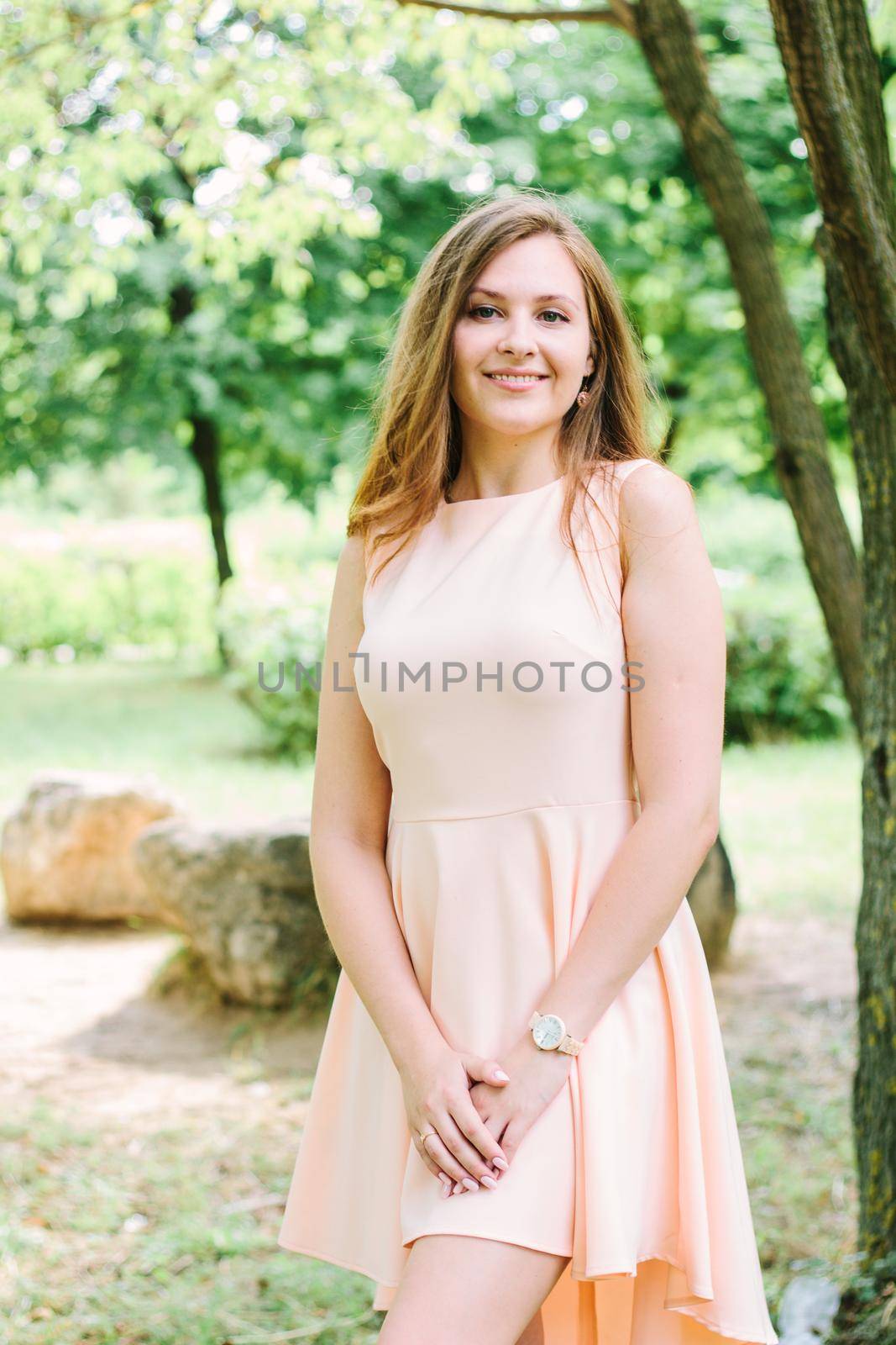 Beautiful young woman standing at a park and smiling
