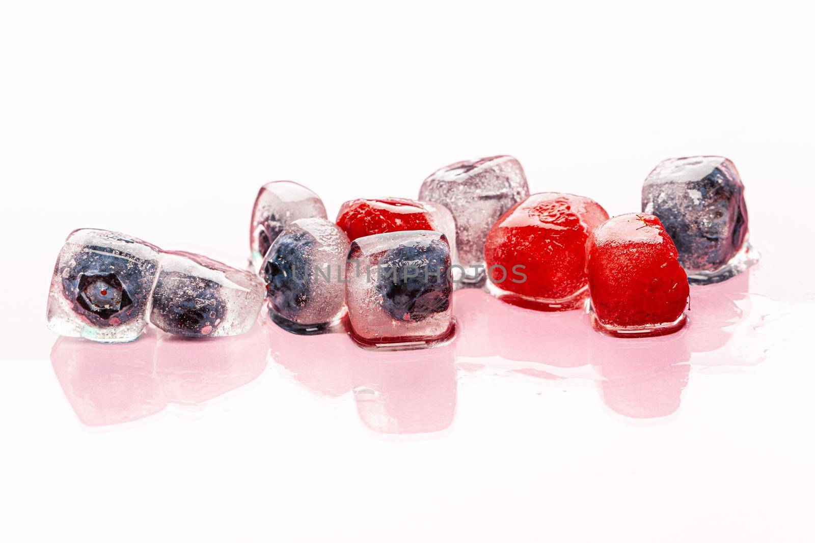 Fresh berries frozen in ice cubes for drinks. Close up.