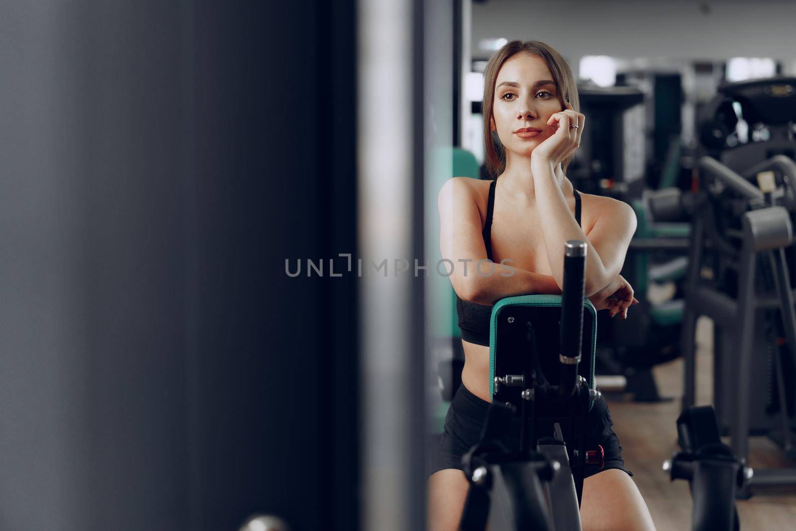 Young beautiful woman training her arms in a gym apparatus in a gym