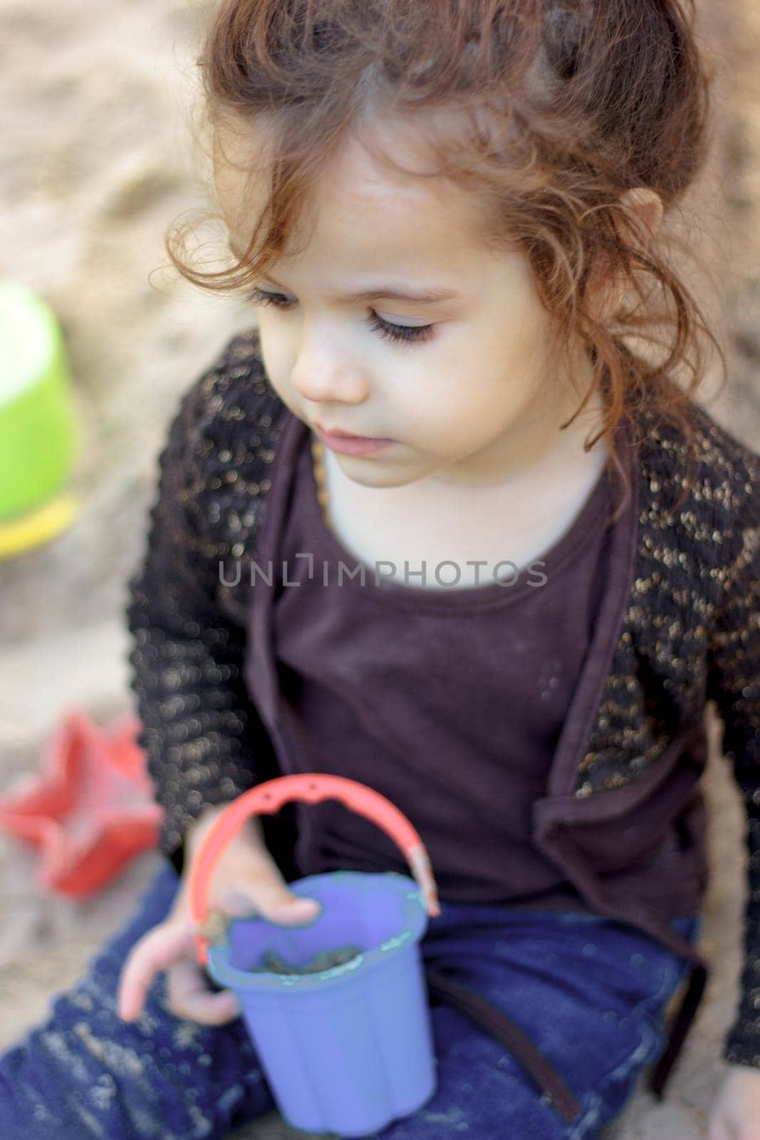 Little kid girl playing with the sand on the playground