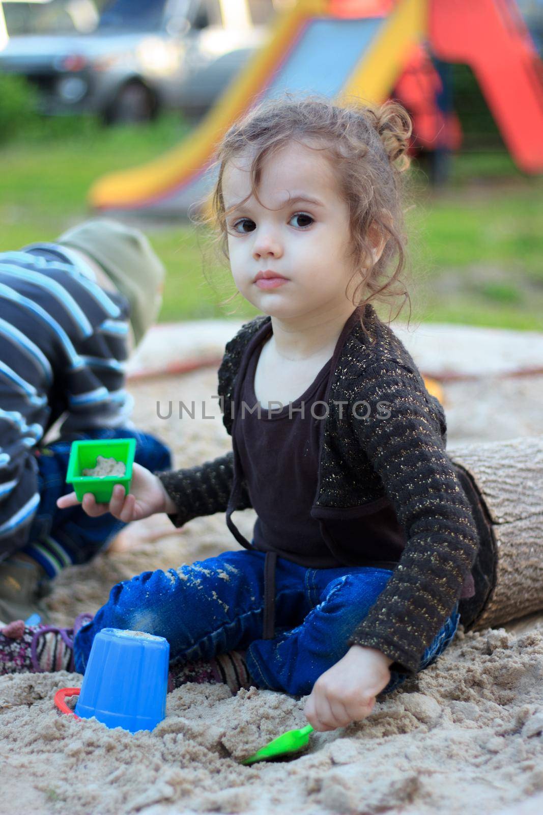 Little kid girl playing with the sand on the playground