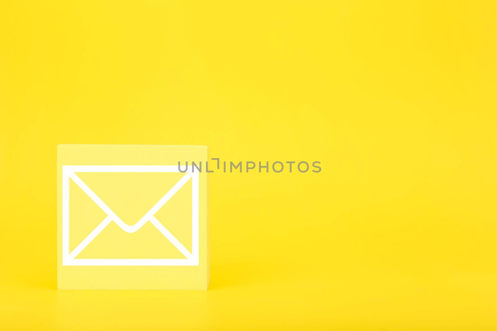 Email marketing, newsletter, promotion information and virtual communication concept. Envelope drawn on small toy cube against bright yellow background with copy space.