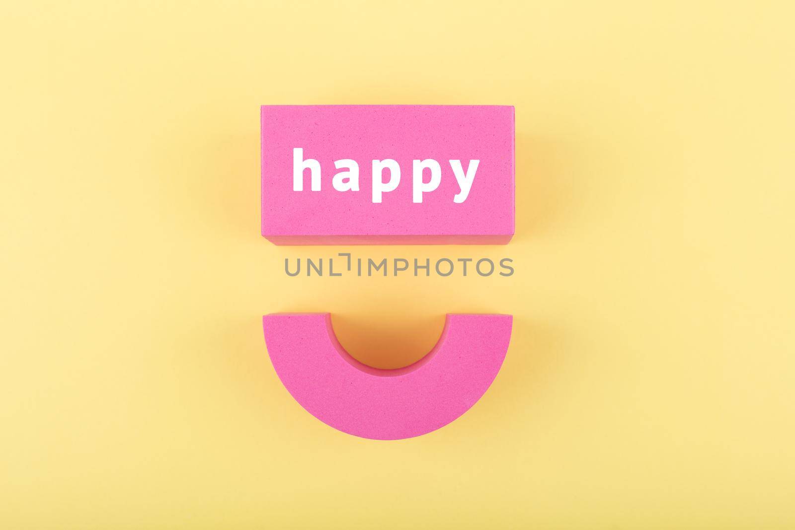 Creative flat lay with pink happy smile symbol made of toy figures on bright yellow background. Concept of Smile day, emotions, emoji or mental health