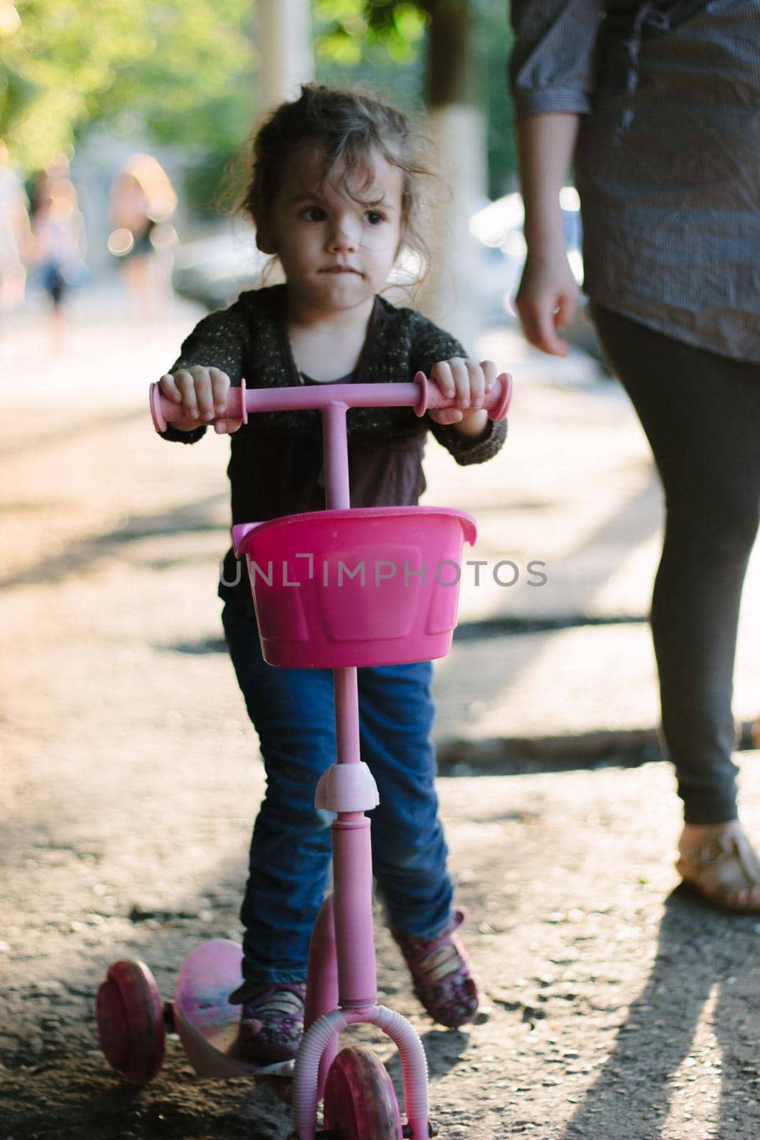 Yong kid girl ride on street on child scooter