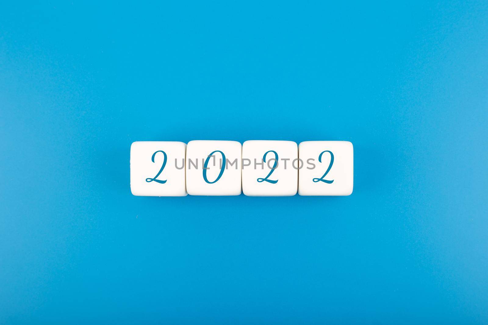 2022 numbers written on white toy cubes in a row as a calendar against bright blue background with copy space. Minimal elegant business style concept of upcoming 2022 year