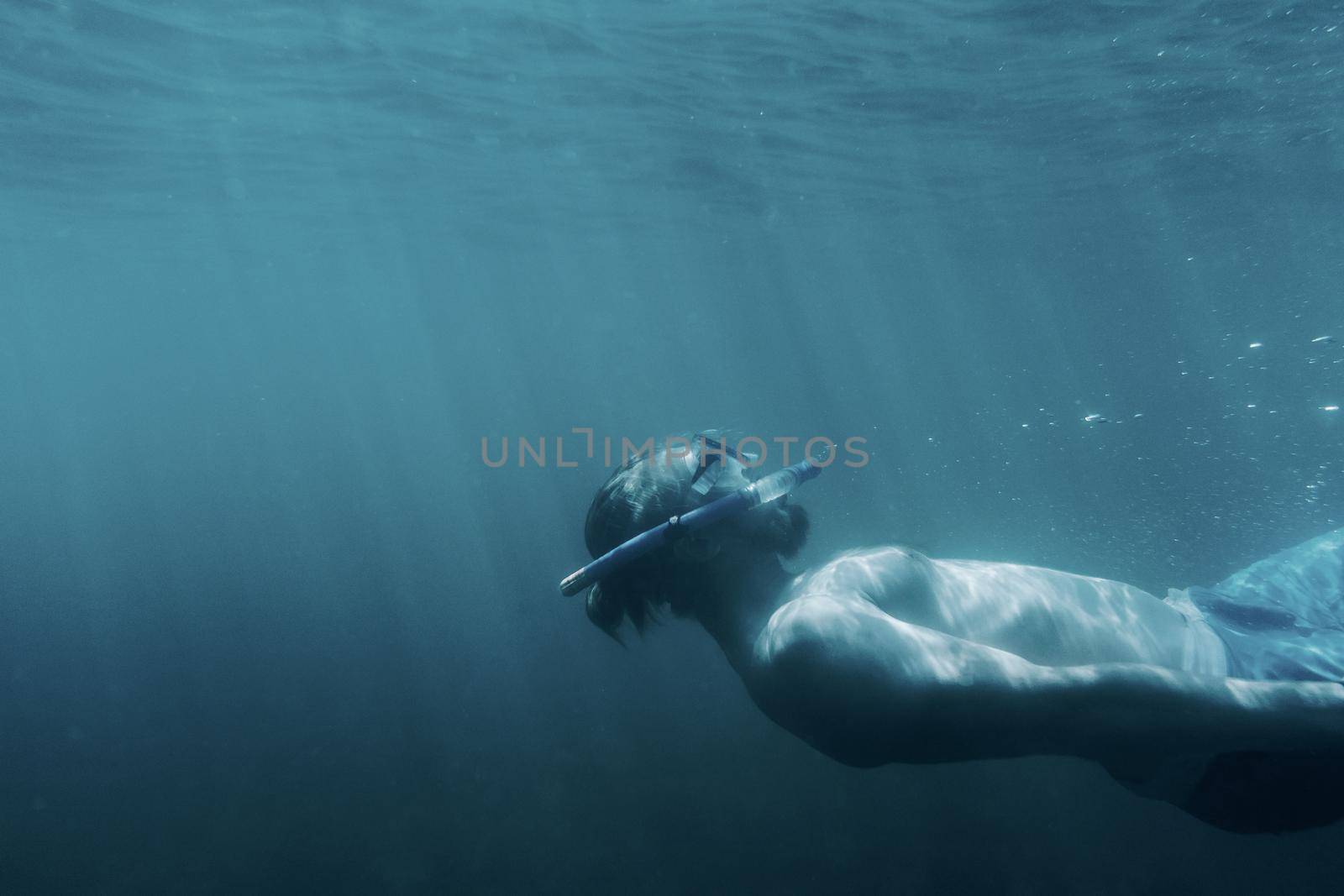 Sporty freediver young man swimming and relaxing underwater.