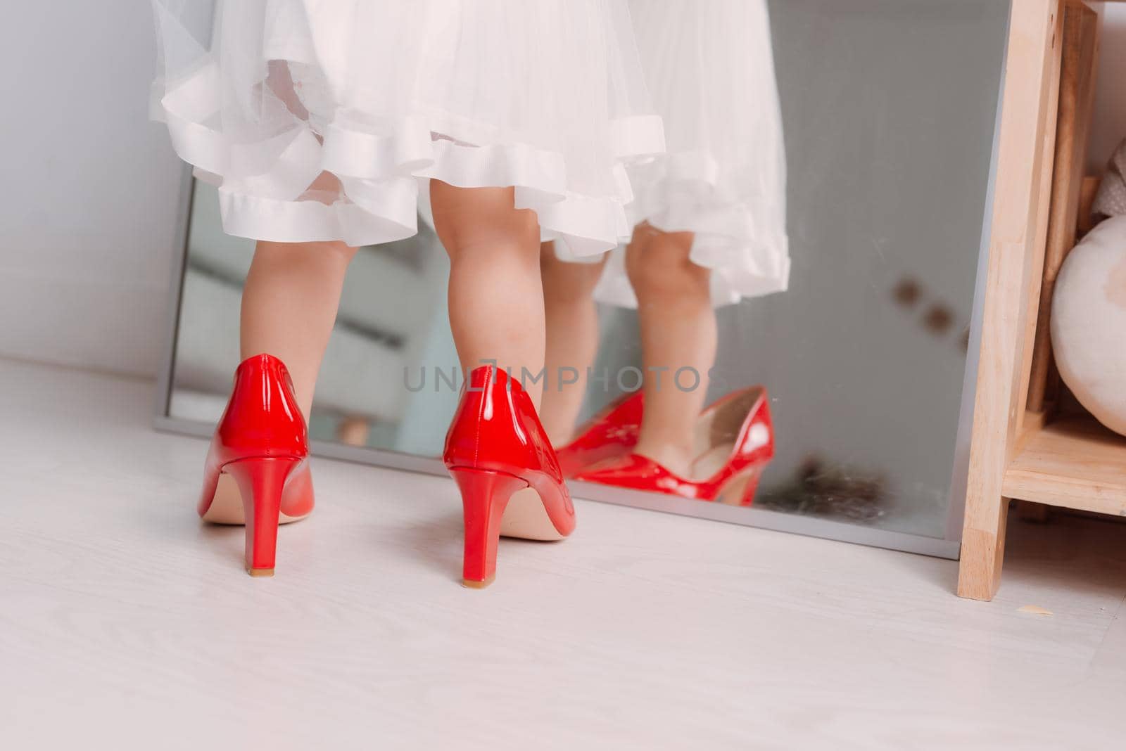 Cute little girl wearing high heeled shoes at home, closeup by makidotvn