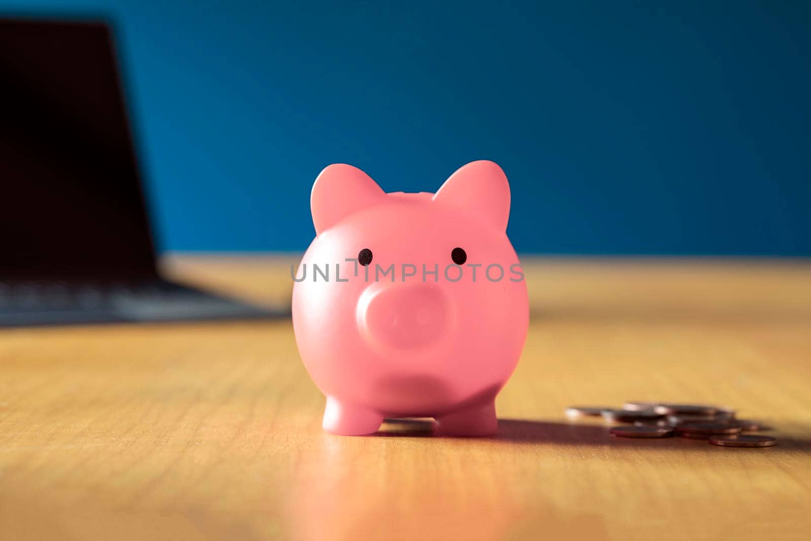 Pink piggy bank on wooden office desk at home with pile of coins, savings,investment business and financial concept close up