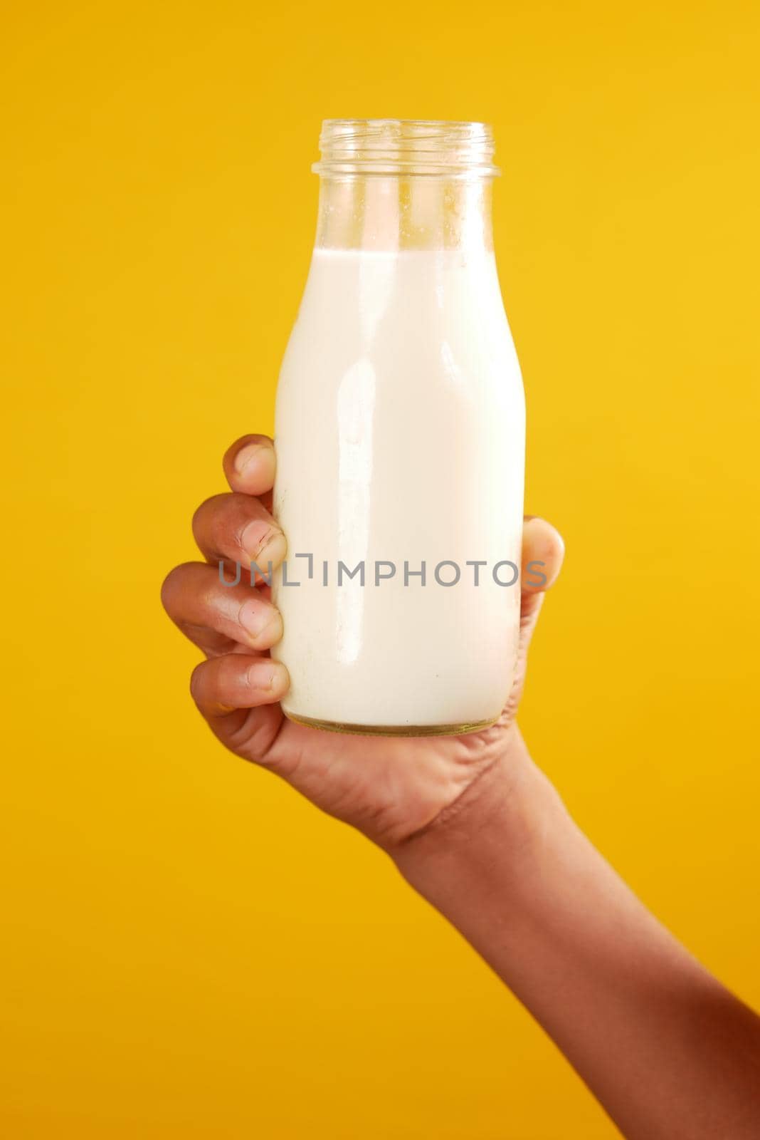 hand hold a milk bottle against yellow background by towfiq007