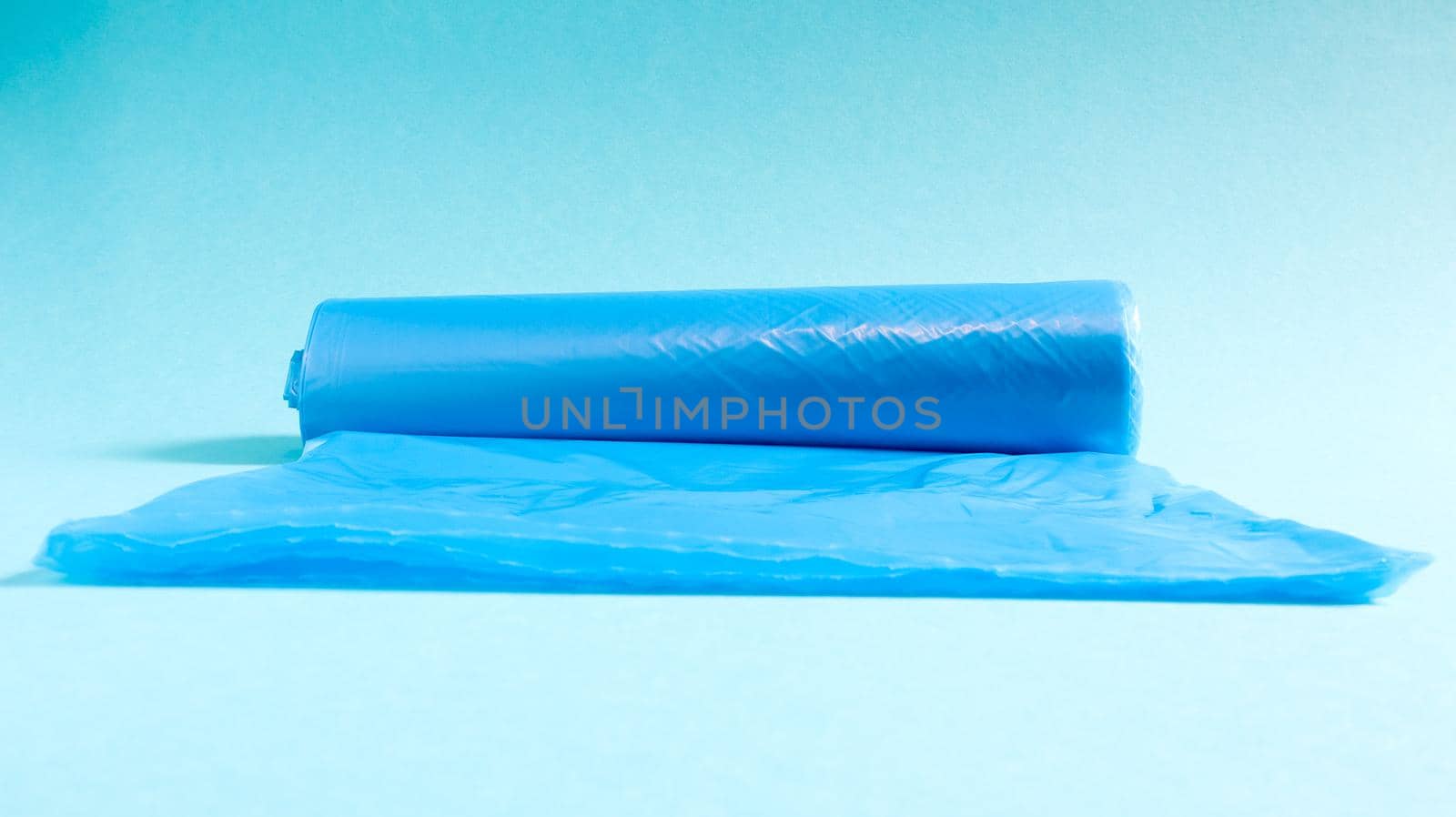 One roll of plastic garbage bags in blue on a blue background. Bags that are designed to accommodate garbage in them and used at home and placed in various garbage containers