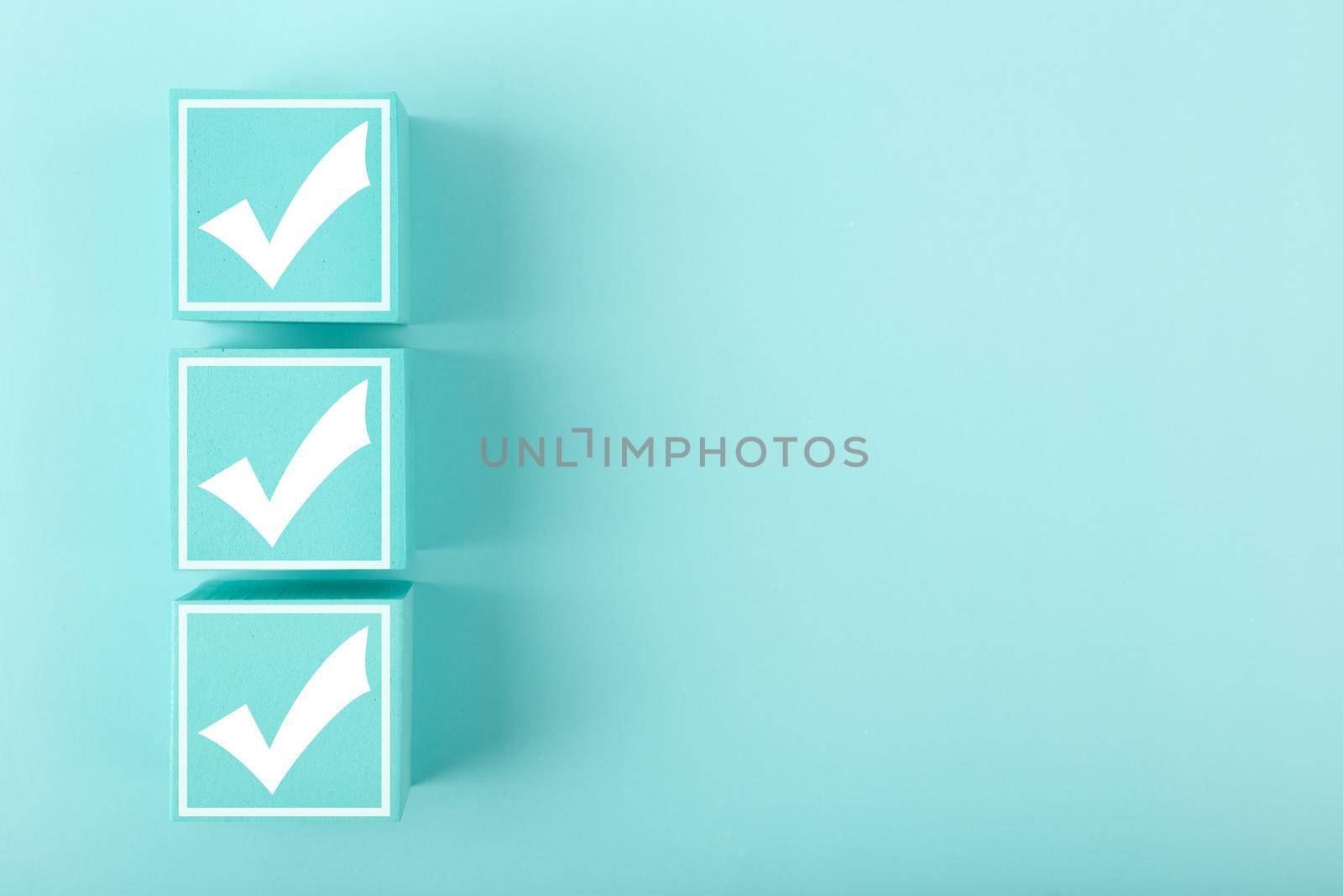 Three white checkmarks on blue cubes against bright pastel blue background with copy space by Senorina_Irina