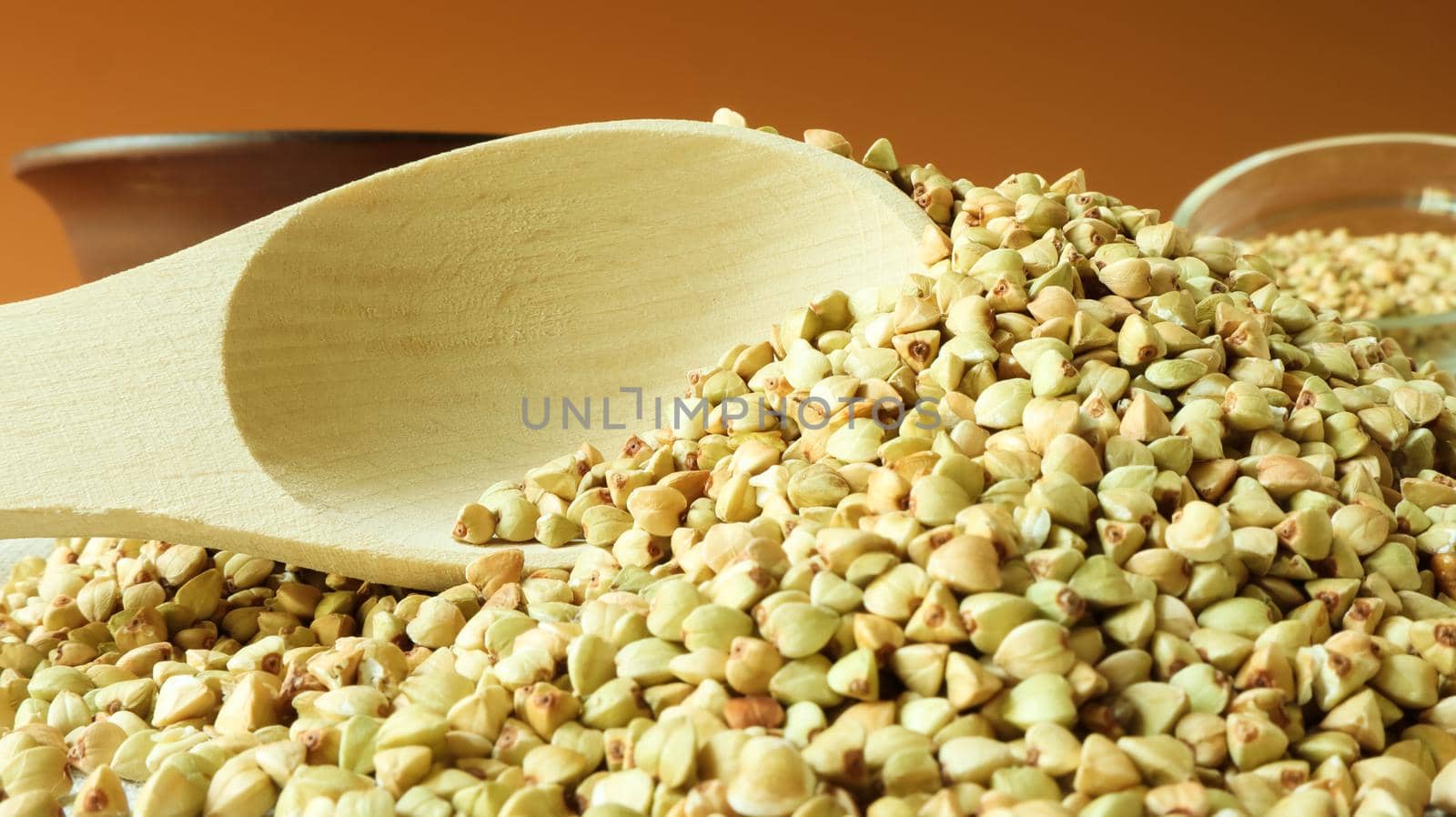 Buckwheat scattered background, raw green cereal in a wooden spoon. Healthy groats. Organic raw non-fried vegetarian food. The concept of a healthy and balanced diet. Diet product. healthy groats