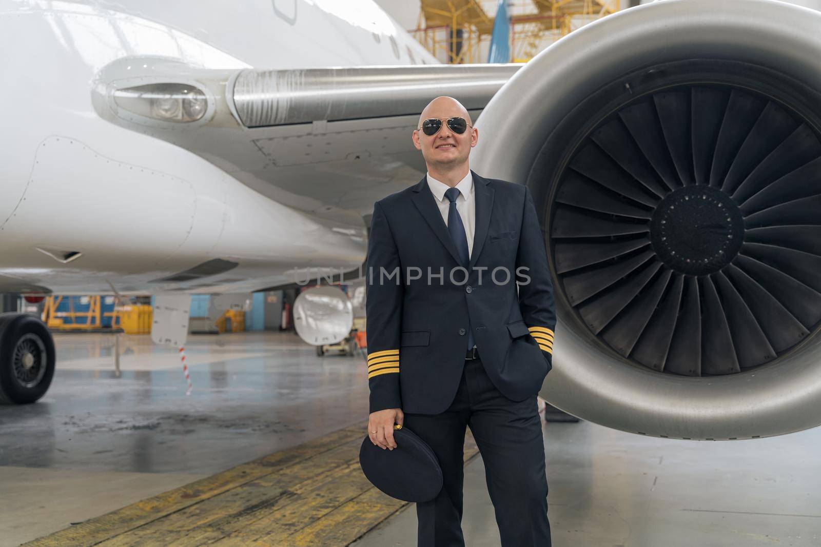 Pilot in black suit posing near the turbine wing of an airplane by Yaroslav_astakhov