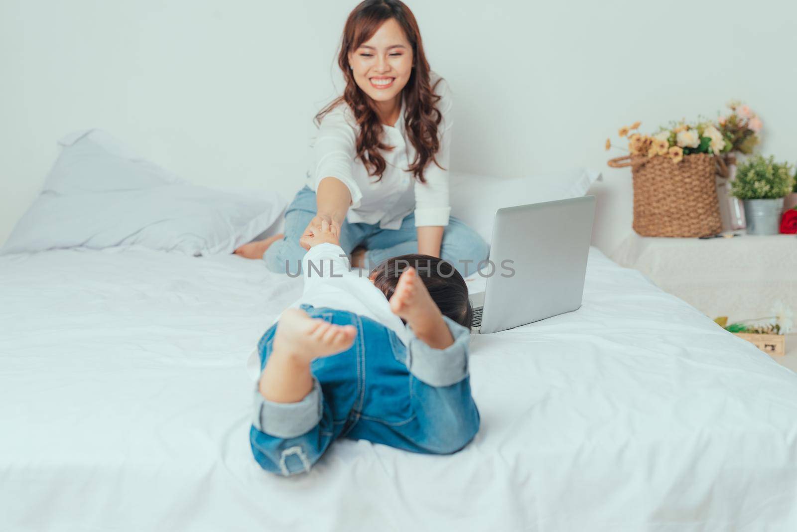 Asian young woman is working busy on laptop while her daughter playing near mother
